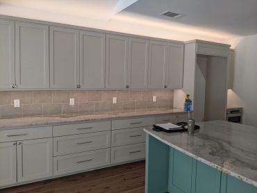 New kitchen with gray cabinets and marble countertops.
