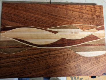 Wooden cutting board with wave-like patterns.