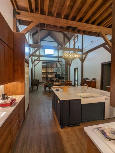 Modern rustic kitchen and dining area under exposed wooden beams.