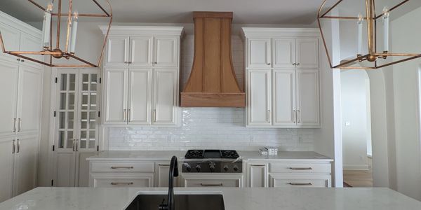 Modern kitchen with white cabinets and wooden range hood.