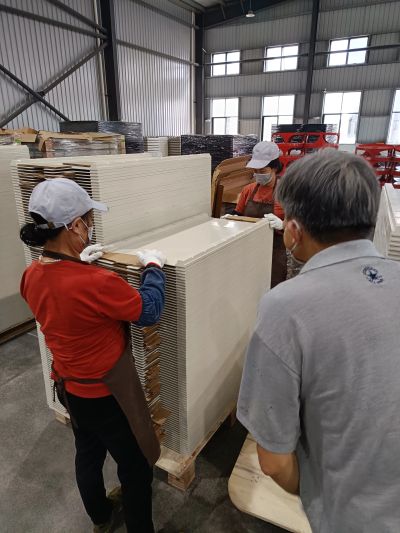 Workers handling large flat panels in a warehouse.