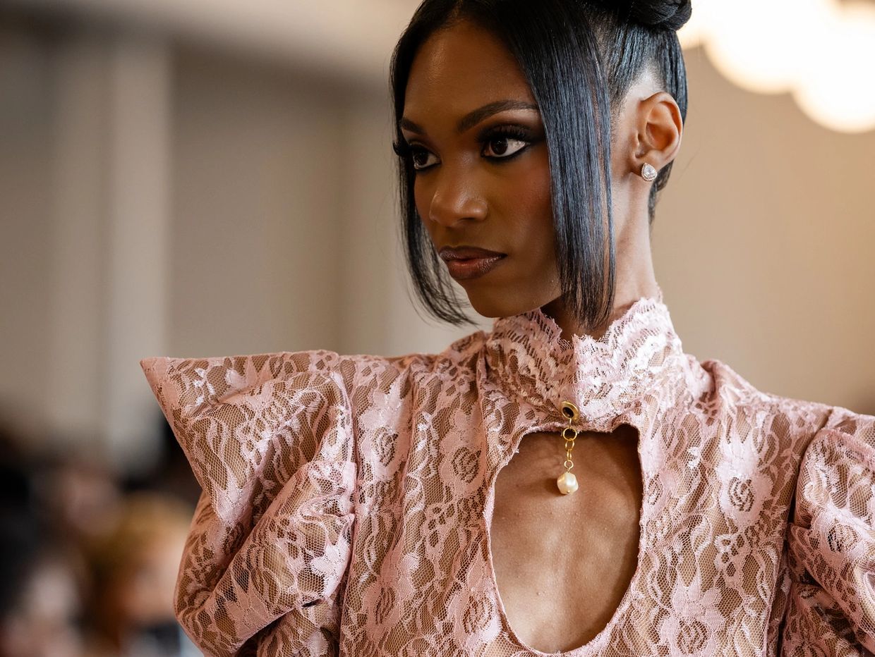 Woman in pink lace dress with pearl detail.