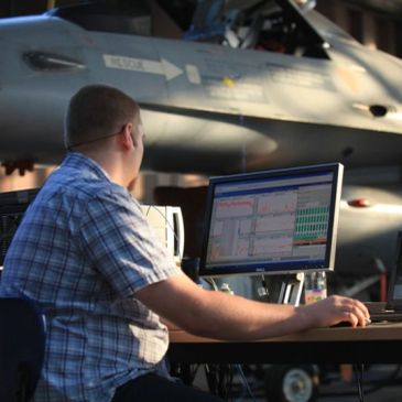 Technician monitoring aircraft systems on a computer in a hangar.