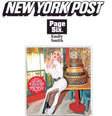 Gigi Gorgeous poses next to a multi-tiered cake.
