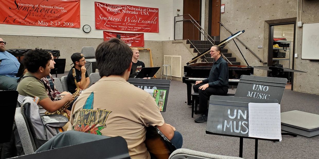 Music students in a classroom with a grand piano and instructor.