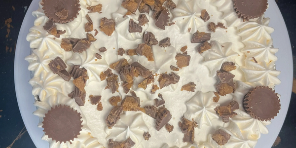 Creamy cake topped with mini peanut butter cups and crumbled chocolate pieces.