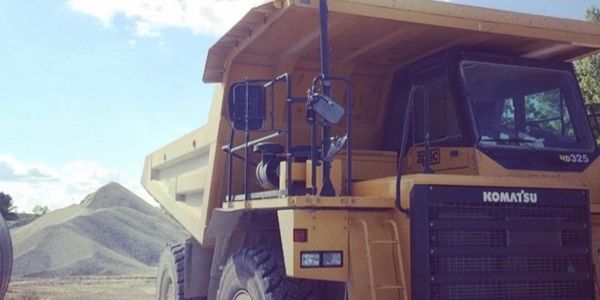 Large yellow Komatsu dump truck at a gravel site.