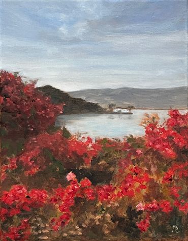 Morning sunrise shines through red flowers popping pink color.  House on the bay in the distance.