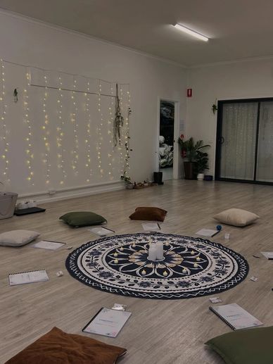 A cozy meditation circle with cushions, notebooks, and a central mandala mat in a softly lit room.