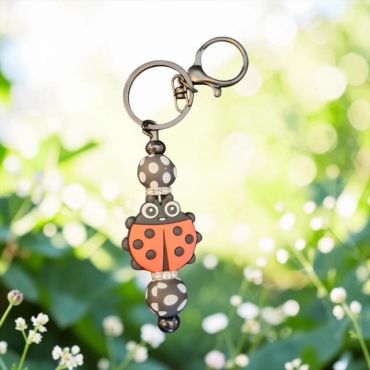 Close-up of a ladybug keychain with beads, hanging outdoors.