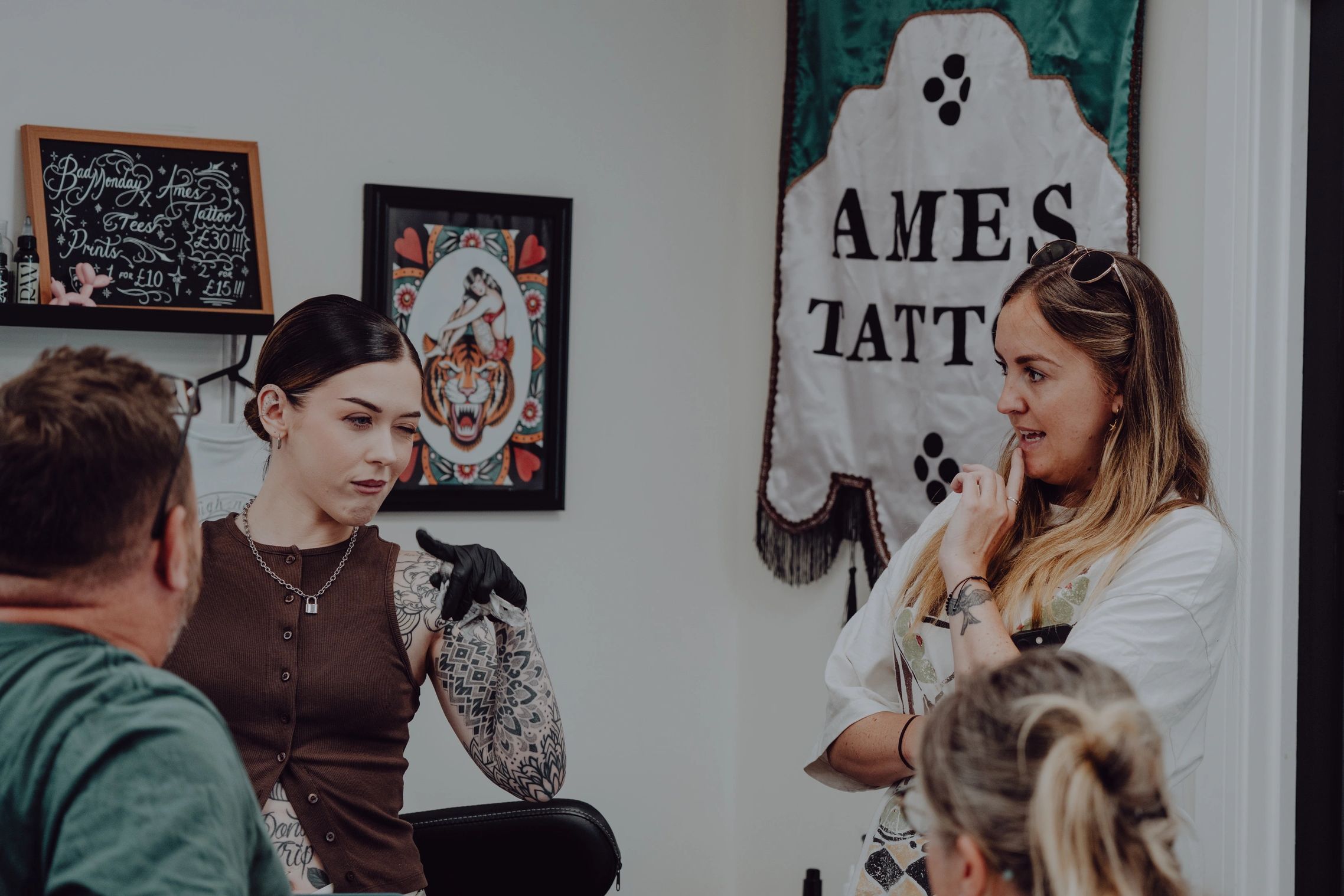 Tattoo artist consulting with clients in a studio.
