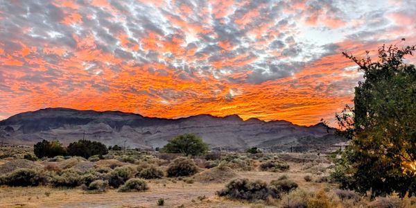 Vibrant orange sunset over desert landscape with mountains.