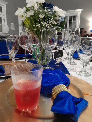 Elegant table setting with blue napkins, glassware, and a floral centerpiece.