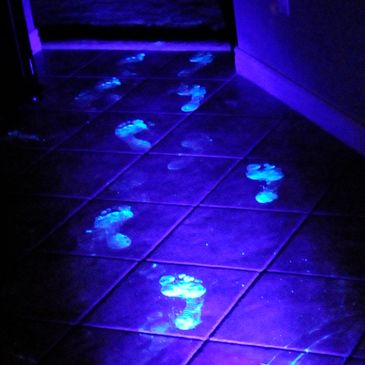 Glowing footprints illuminated on a tiled floor under blacklight.