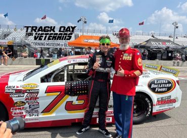 Racecar driver and Marine in uniform pose beside car at Track Day for Veterans event.