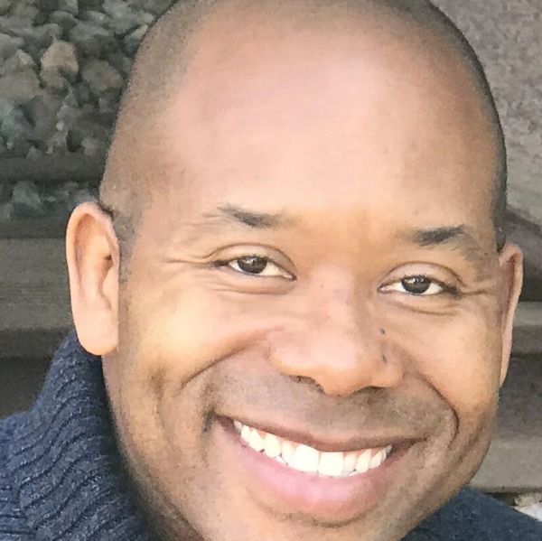 Close-up of a smiling man wearing a dark knit sweater.