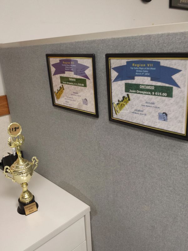 Trophy and framed awards for Juan Orospeza on a wall and desk.