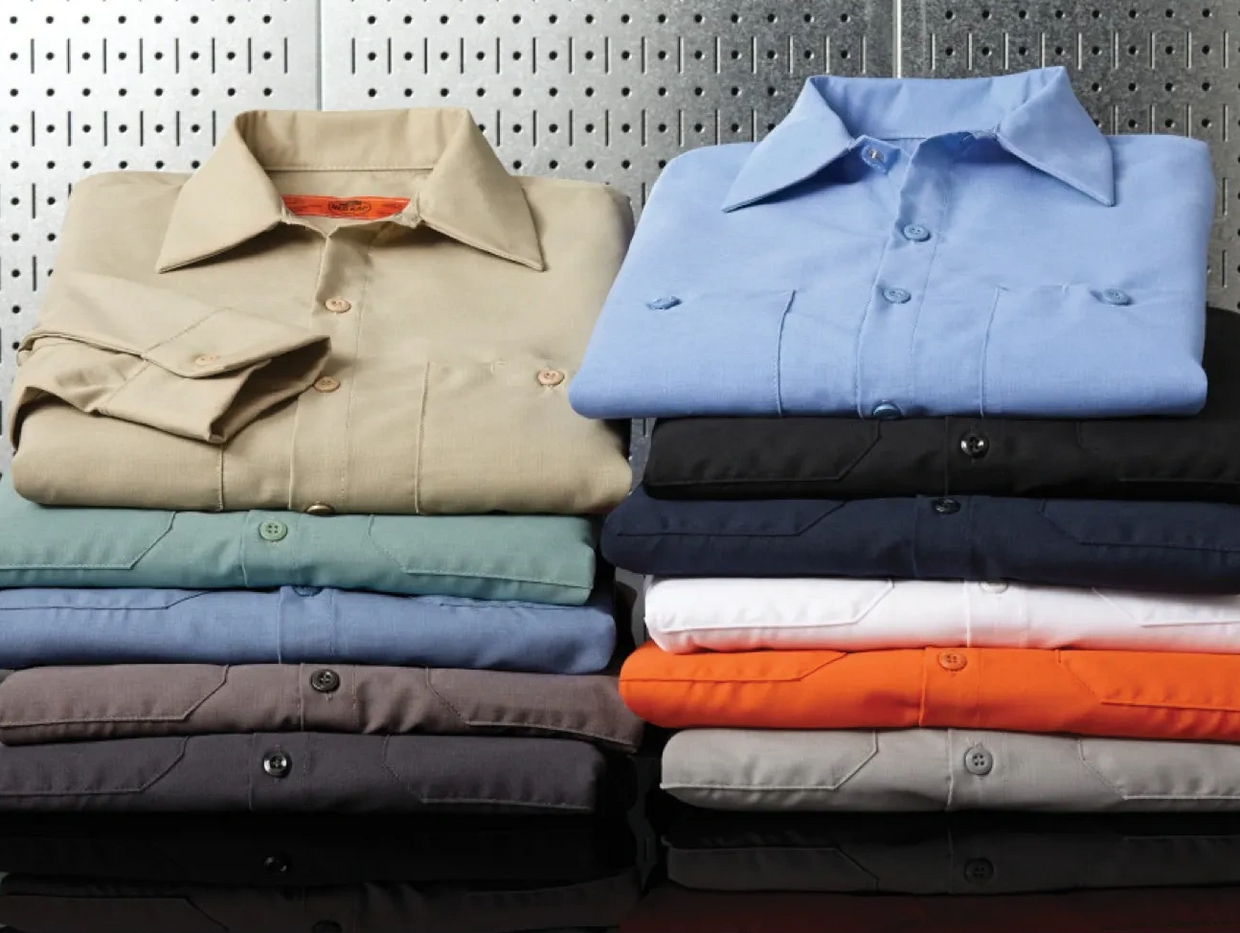 Two stacks of neatly folded colorful button-up shirts on a reflective surface.
