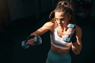 Woman exercising with dumbbells in a focused workout session.