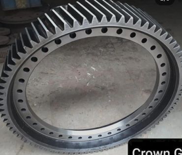 A large black metal gear ring with evenly spaced holes and teeth.