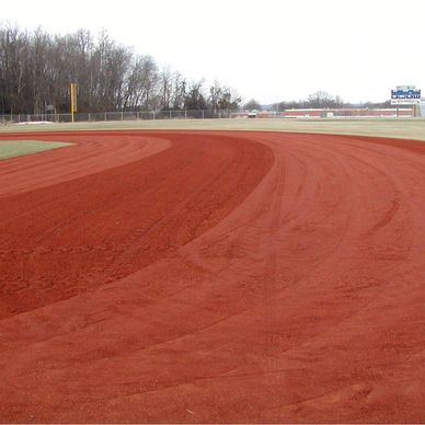 Curved red clay running track on an overcast day.