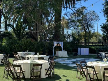 Outdoor event setup with tables and chairs on green lawn.