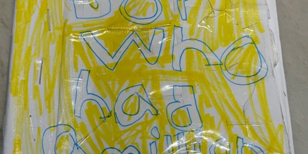 A colorful handwritten note with blue letters on a yellow background.