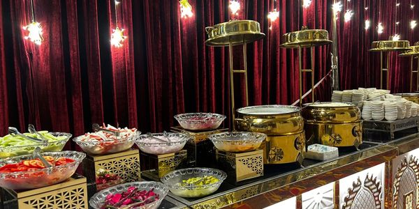 Elegant buffet setup with various salads and warm dishes under golden lids.