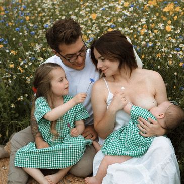 A family enjoying a tender moment in a flower field with children in matching green dresses.
