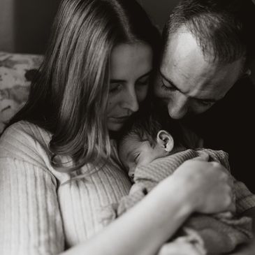 A tender moment of parents lovingly holding their newborn baby.