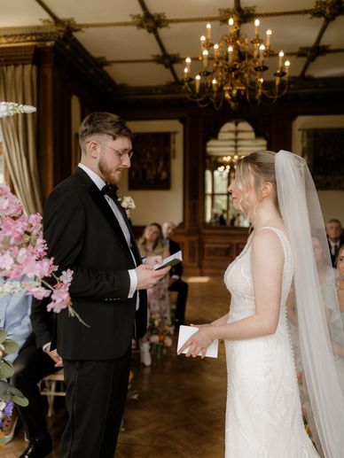 Bride and groom exchange vows in an elegant, vintage-style room.