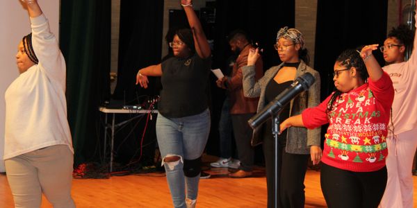 Group of people dancing or practicing on stage with raised arms.
