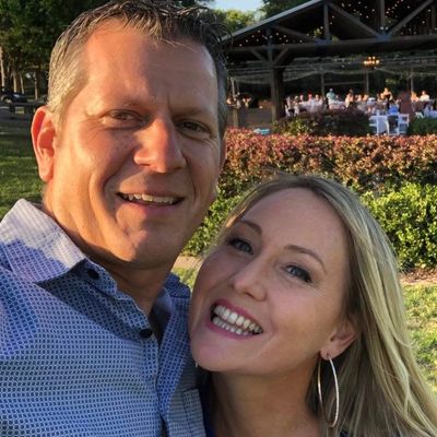 A smiling couple enjoying an outdoor event in sunny weather.