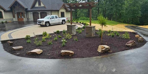 Spacious driveway and landscaped garden with pergola.