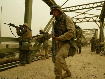 Soldiers in combat gear securing a bridge during a mission.
