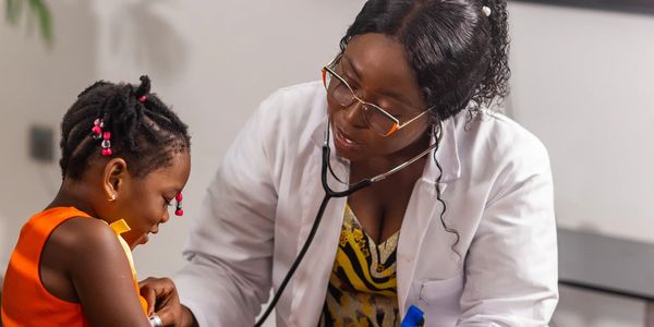 Nurse engages with child with a stethoscope in a playful check-up.
