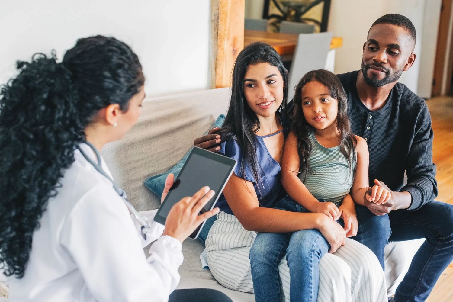 A family consulting with a nurse using a tablet at home.