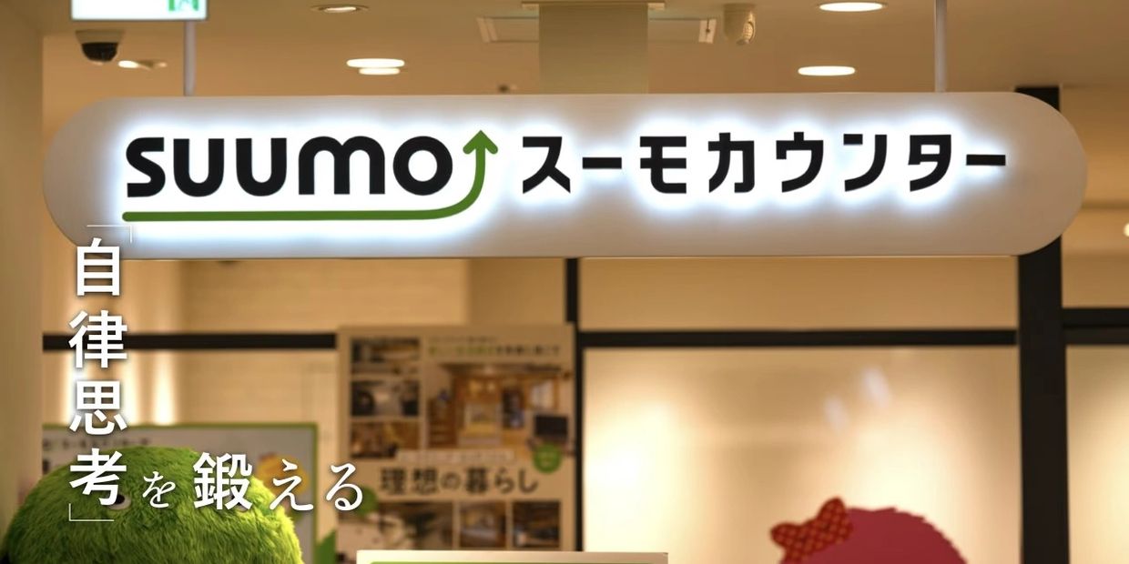 Illuminated SUUMO sign with Japanese text inside a building.