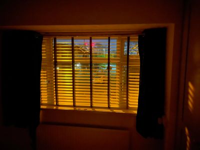 Window with blinds partially open, illuminated by warm light.