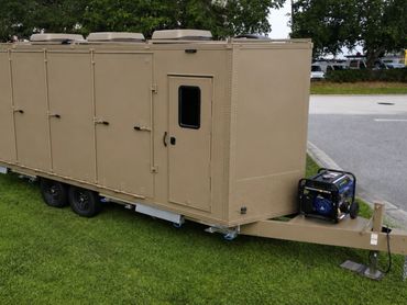 Beige mobile trailer with multiple doors and a generator on the front platform.