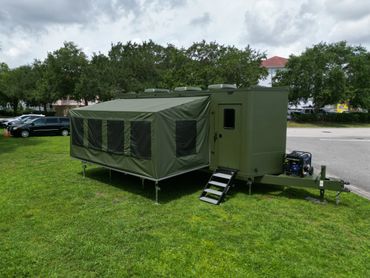 Military green mobile field unit with extended canvas sides and steps.