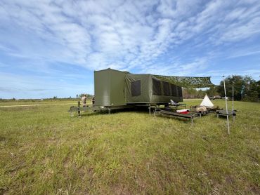Green military tent set up in an open field.