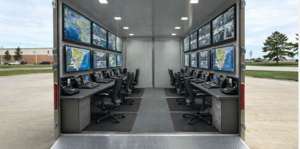 High-tech mobile control room with multiple monitors and workstations inside a trailer.