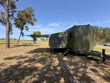 Green mobile trailer in a sunny open area.