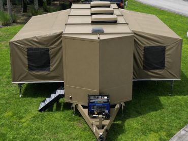 Military-style expandable camper trailer with canvas sides and generator at the front.