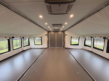 Interior of a spacious, well-lit trailer with multiple windows and air vents.