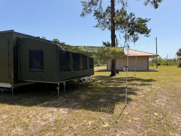 Military-style tent set up near a small building.