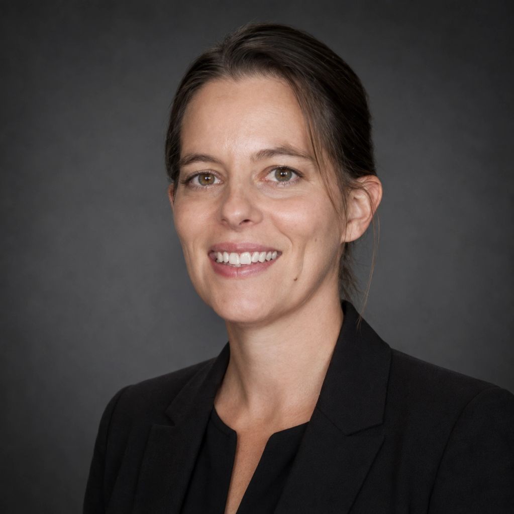 Professional woman smiling in a black blazer against a dark background.
