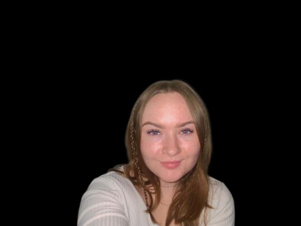 Young woman with light brown hair smiling against a black background.