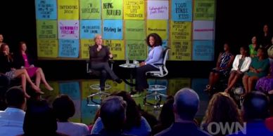 Two women having a conversation on a talk show stage with an audience.